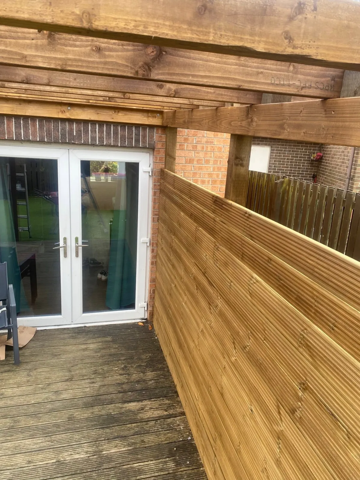 Covered timber garden structure with slatted side screening