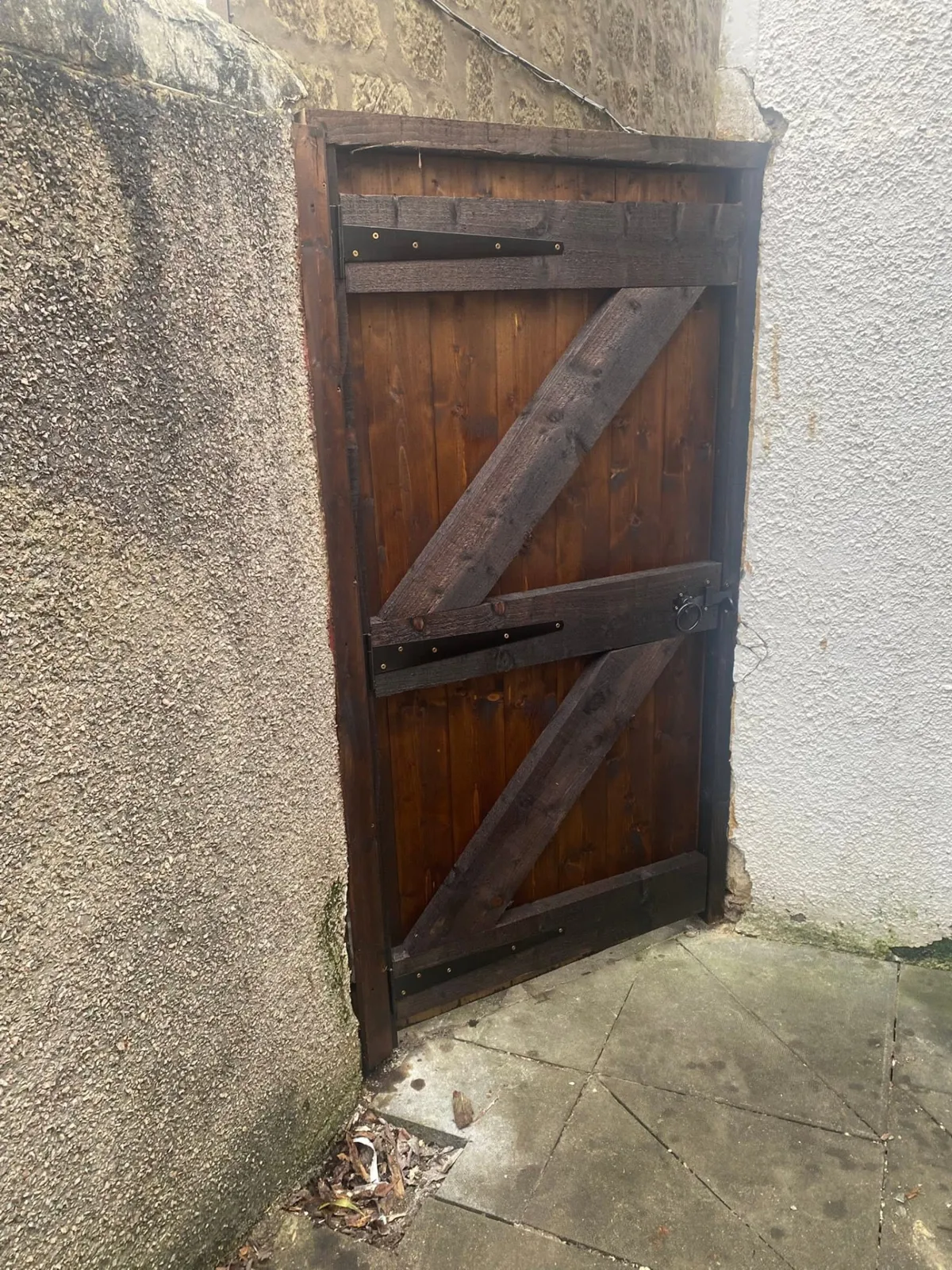 Dark-stained timber gate fitted between two walls